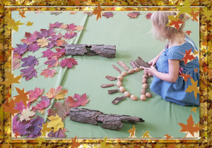 Dziewczynka układa jeża z orzechów i kory.
